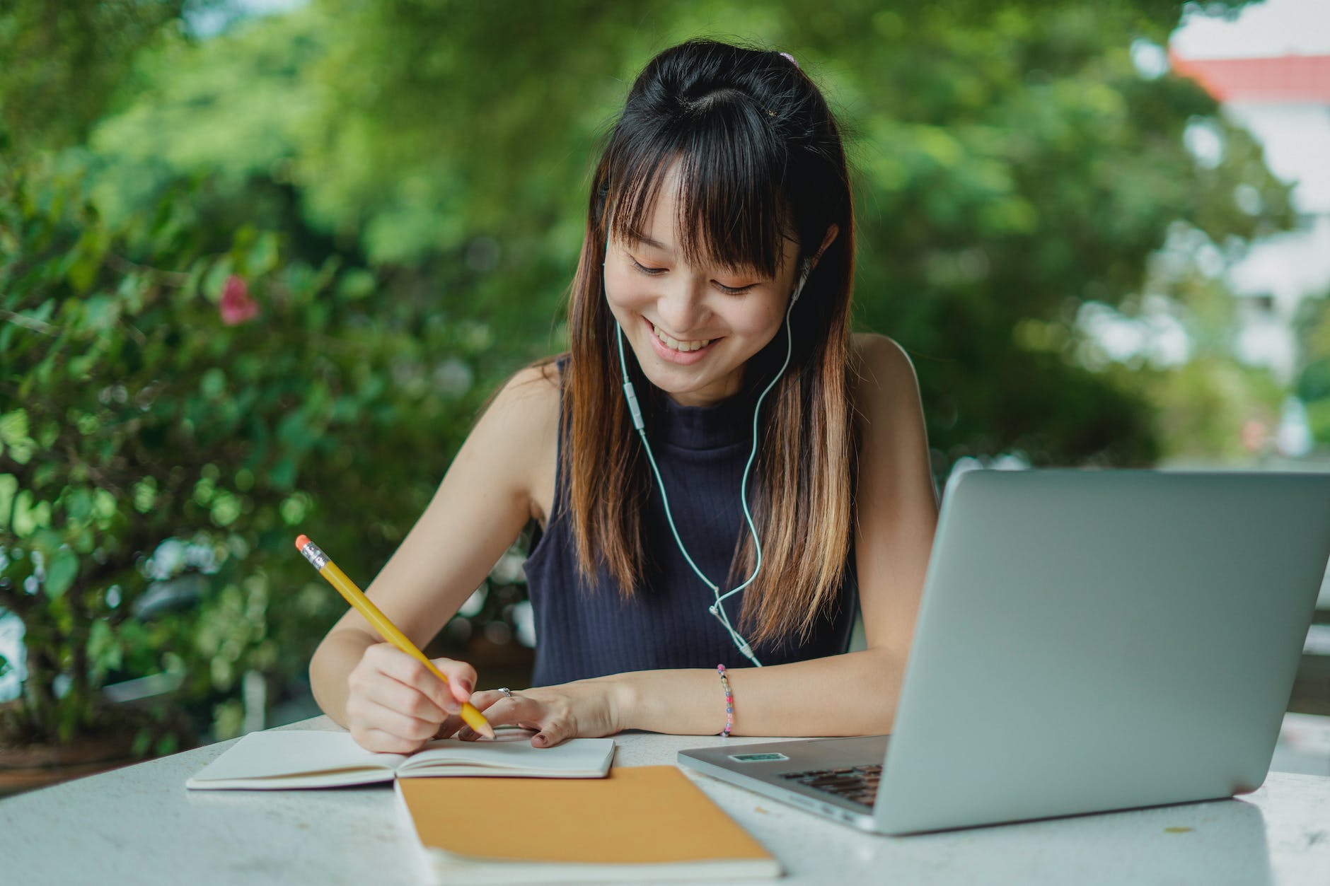 happy young asian student doing homework and listening to music with earphones