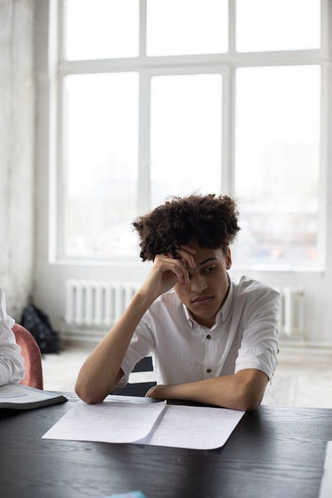 pensive black man working on essay in light room